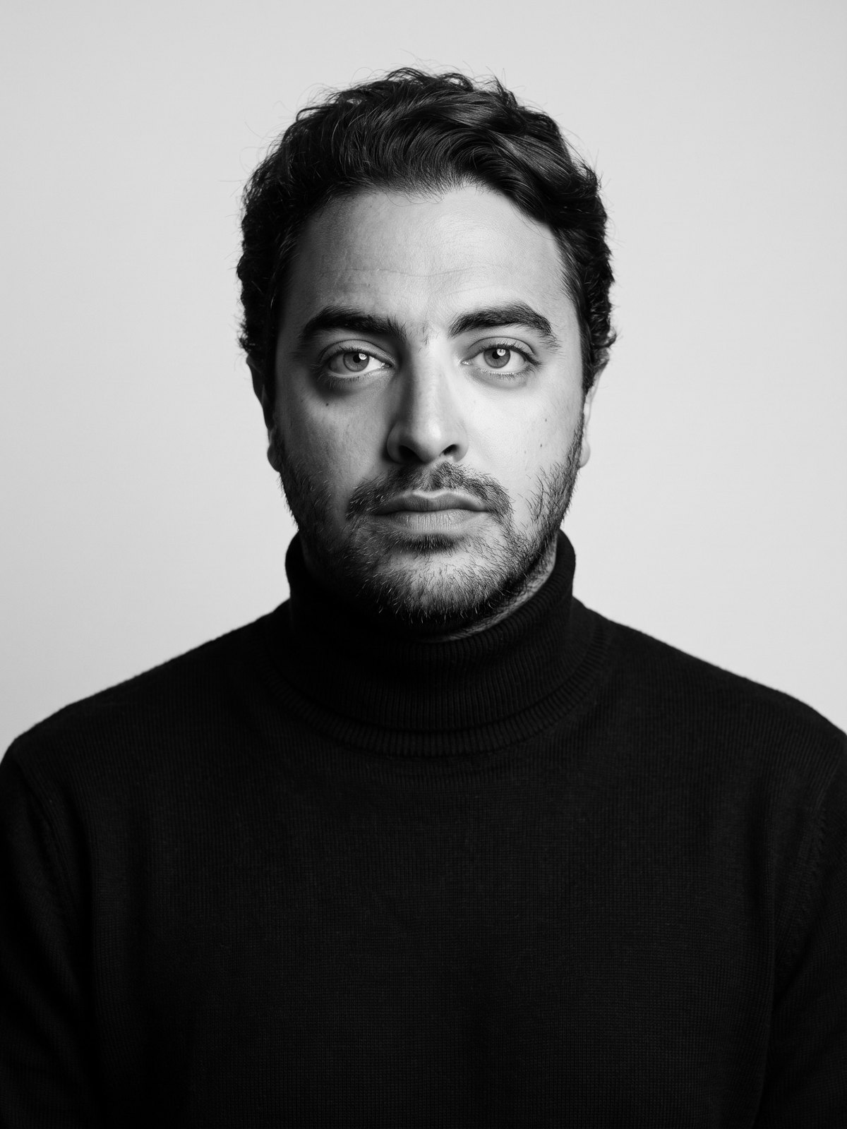 Hazem Zarka in a black turtleneck, black-and-white studio portrait